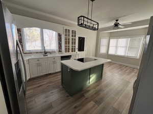 Kitchen featuring sink, a center island, ornamental molding, black appliances, and white cabinets