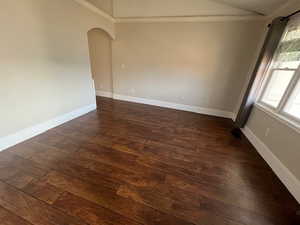 Unfurnished room with ornamental molding, lofted ceiling, and dark hardwood / wood-style flooring