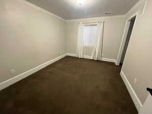 Carpeted empty room featuring ornamental molding