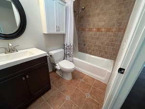 Full bathroom featuring tile patterned floors, vanity, toilet, and shower / tub combo