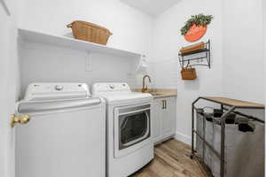 Washroom featuring sink, light hardwood / wood-style flooring, cabinets, and independent washer and dryer