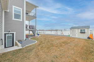 View of yard featuring a balcony and a storage unit