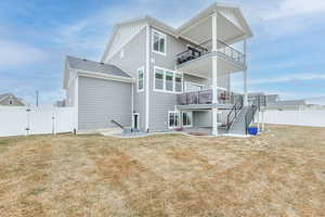 Rear view of property with a balcony and a lawn