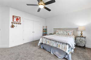 Bedroom with a closet, ceiling fan, and carpet flooring