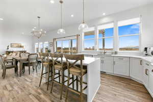 Kitchen featuring a breakfast bar, decorative light fixtures, white cabinetry, sink, and a center island