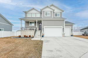 Craftsman inspired home featuring a garage, covered porch, and a front yard