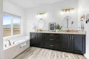 Bathroom with hardwood / wood-style flooring, a tub to relax in, vanity, and a mountain view