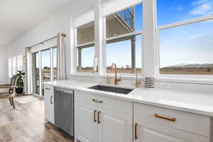 Kitchen with white cabinetry, wood-type flooring, sink, and stainless steel dishwasher