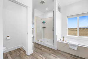 Bathroom featuring wood-type flooring, toilet, and separate shower and tub