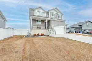 View of front of property featuring a porch, a garage, and a front yard