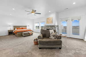 Carpeted bedroom with a stone fireplace, access to outside, and ceiling fan