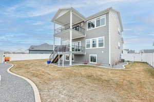 Back of house with a balcony and a lawn