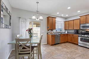 Kitchen featuring sink, decorative light fixtures, a notable chandelier, and appliances with stainless steel finishes