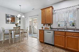 Kitchen featuring pendant lighting, sink, light tile patterned floors, dishwasher, and a chandelier