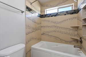 Bathroom with tiled shower / bath and toilet