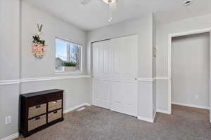 Carpeted bedroom with ceiling fan and a closet