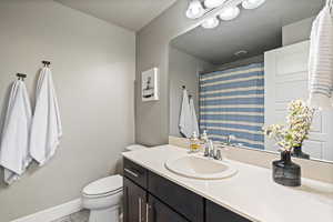 Bathroom with vanity, walk in shower, tile patterned floors, and toilet