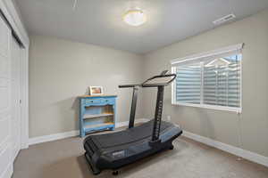 Exercise area with a textured ceiling and carpet flooring