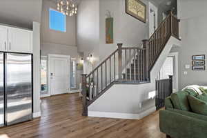 Foyer entrance featuring wood-type flooring, a towering ceiling, and a notable chandelier