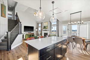 Kitchen with lofted ceiling, a center island, hanging light fixtures, light wood-type flooring, and ceiling fan