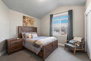 Carpeted bedroom featuring lofted ceiling and a closet