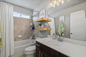 Full bathroom featuring shower / tub combo with curtain, vanity, and toilet