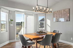 Dining space with vaulted ceiling and wood-type flooring