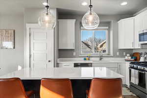 Kitchen featuring appliances with stainless steel finishes, a center island, white cabinets, and decorative light fixtures