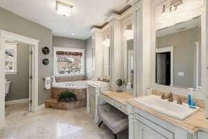 Master Bathroom with a relaxing tiled tub, vanity, and toilet