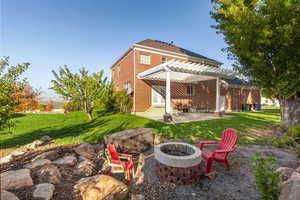Rear view of property with a patio area, a lawn, a pergola, and brick siding