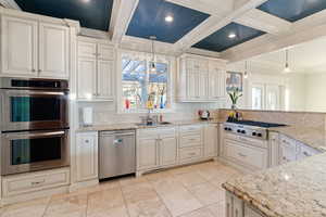 Kitchen featuring coffered ceiling, sink, decorative light fixtures, stainless steel appliances