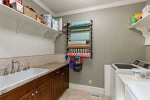 Laundry Room with sink, crown molding, cabinets, washing machine and clothes dryer, and light tile patterned flooring