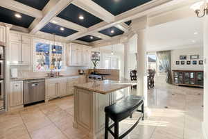 Kitchen featuring a breakfast bar, hanging light fixtures, stainless steel appliances, light granite counters, and coffered ceiling