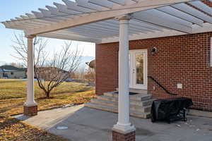 View of patio with grilling area and a pergola