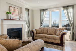 Living room with a tile fireplace, ornamental molding, and light marble tiled patterned flooring