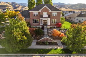 Colonial-style house with stairs, a mountain view, and brick siding