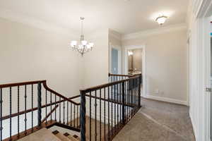 Stairway featuring ornamental molding, carpet, and an inviting chandelier