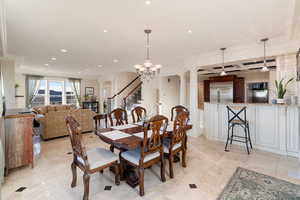 Dining area with an inviting chandelier, ornamental molding, and decorative columns