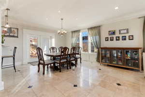 Dining room with an inviting chandelier, crown molding, and light marble tile patterned floors