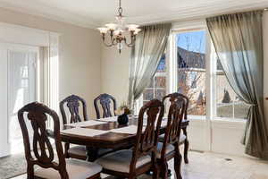 Dining space with an inviting chandelier, a healthy amount of sunlight, and crown molding