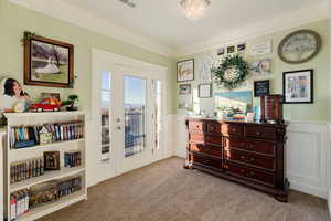 Seating area in master bedroom with ornamental molding and light colored carpet