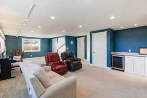 Living room featuring light carpet, track lighting, beverage cooler, and bar area