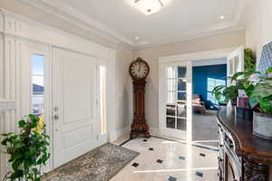 Marble tiled foyer entrance with ornamental molding and plenty of natural light