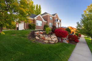 View of front of property featuring a front yard, brick siding, and an attached garage