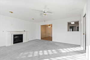 Unfurnished living room featuring ceiling fan and light carpet