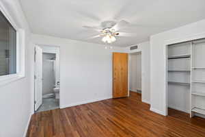 Unfurnished bedroom featuring ceiling fan, ensuite bath, and dark hardwood / wood-style flooring