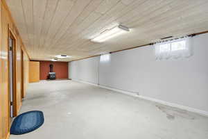 Basement featuring wooden ceiling and a wood stove