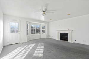 Unfurnished living room featuring ceiling fan and light carpet