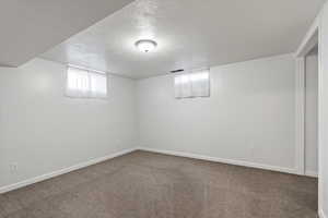 Basement with carpet flooring and a textured ceiling