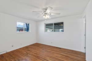 Spare room featuring dark wood-type flooring and ceiling fan